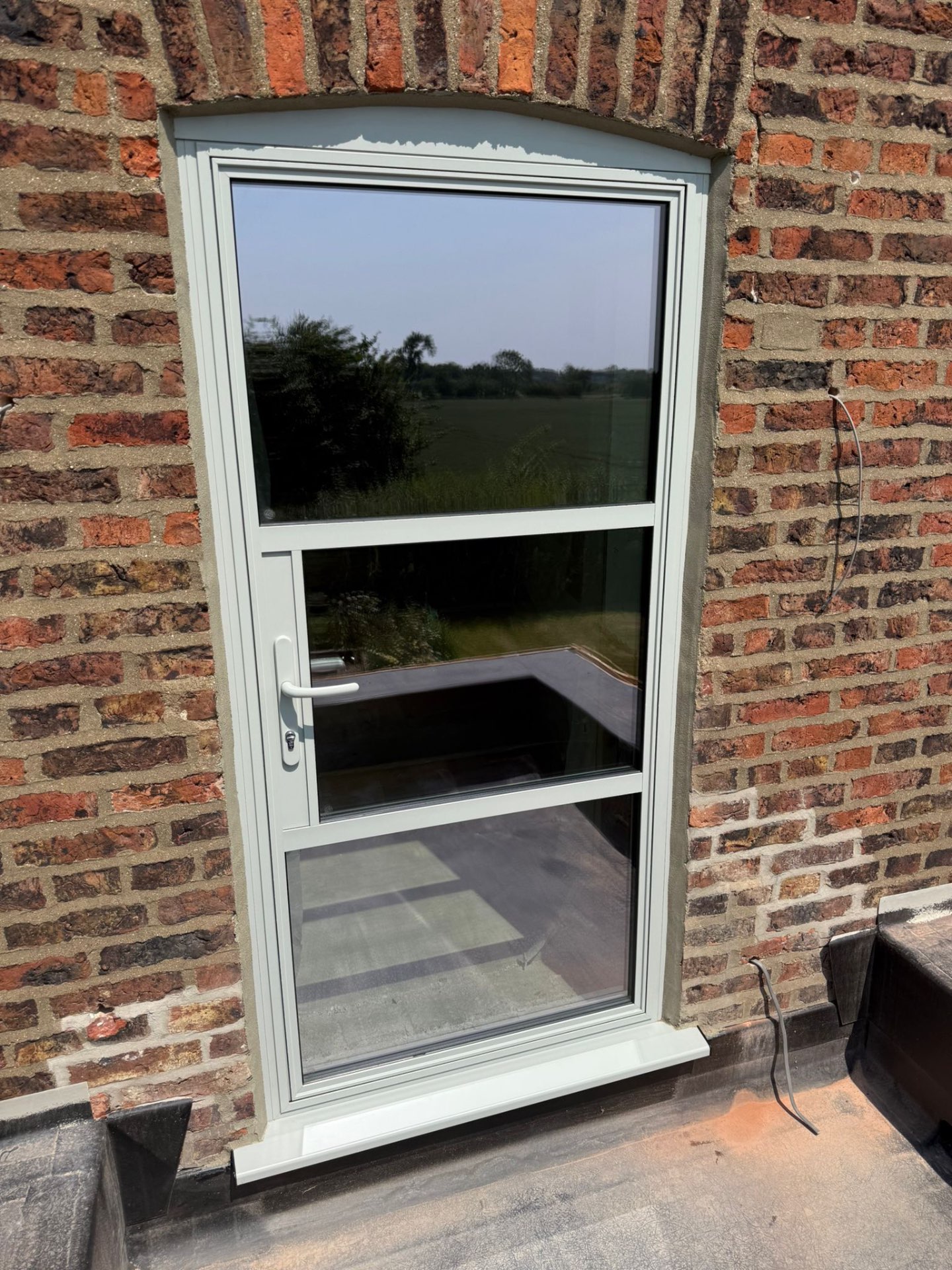 Chalk-white aluminium window in an arched brick opening