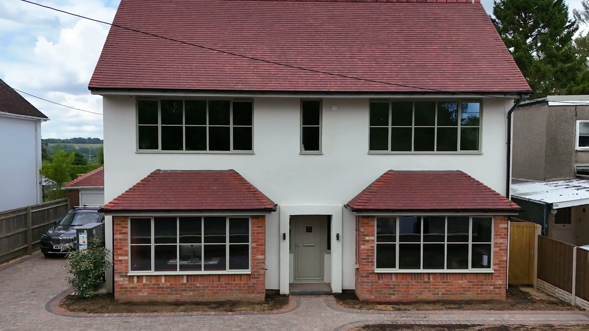 Bay window detail, agate-grey frames against red brick and white render