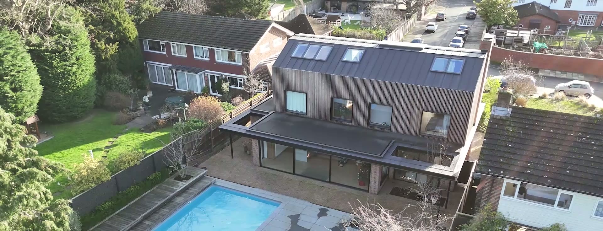 Aerial view — whole-house black aluminium glazing over a timber-clad remodel