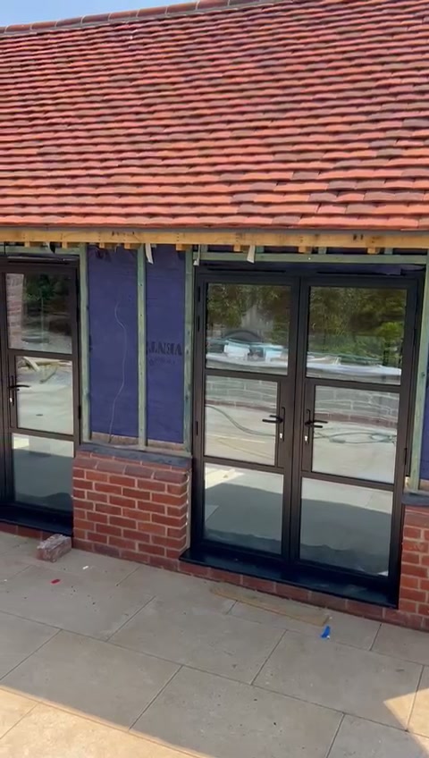 Paired French doors with slim aluminium frames set under the oak lintel